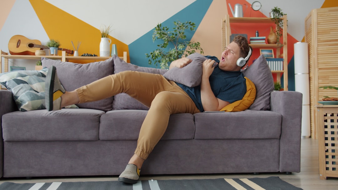 man relaxing on a couch with a laptop after a vasectomy